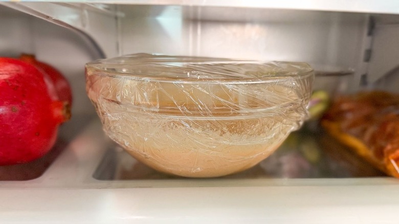 BBQ in a bowl chicken salad dressing in glass bowl with plastic wrap in refrigerator