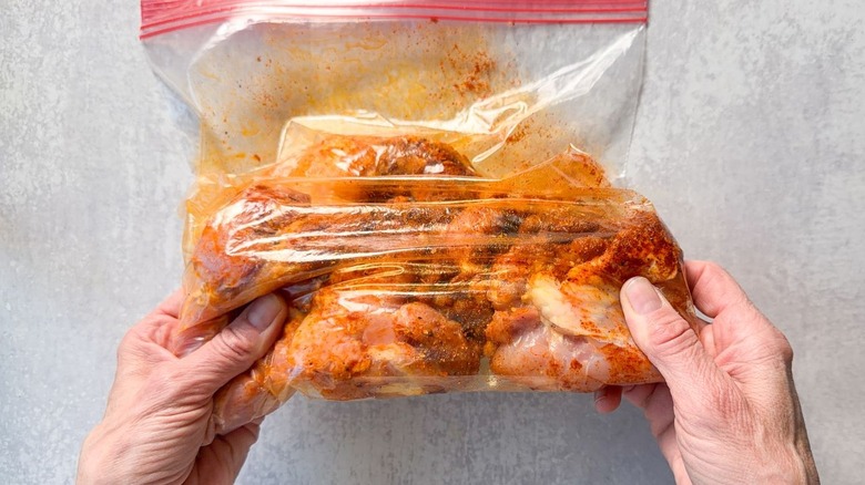 Tossing chicken thighs with dry rub in ziplock bag