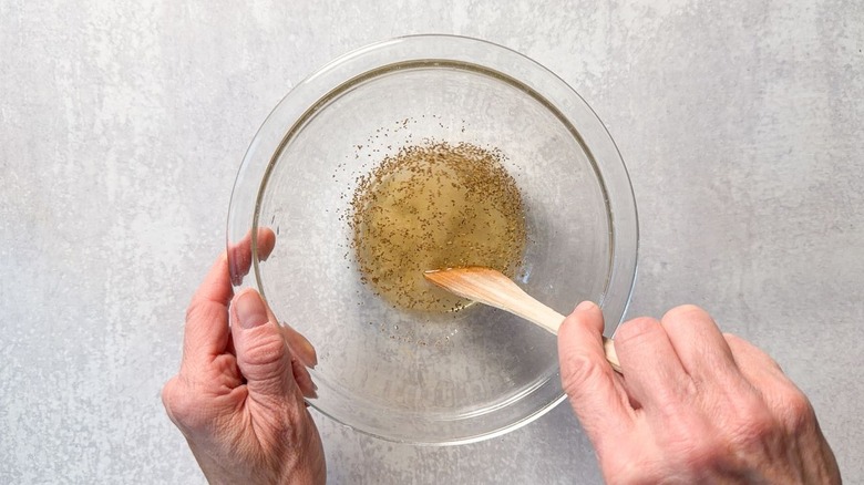 Mixing marinade for cucumber and onion slices in glass bowl