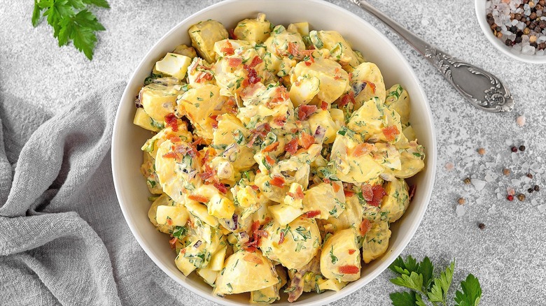 Creamy potato with herbs and bacon in a white bowl