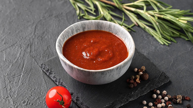 Homemade BBQ sauce in a small gray bowl over a black, square serving plate