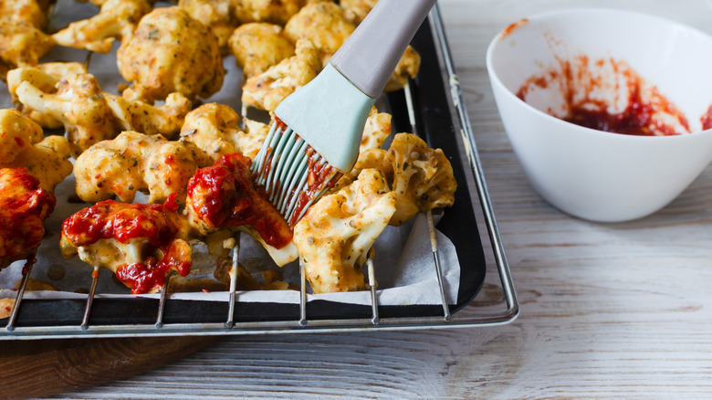 cauliflower in batter with buffalo sauce preparing for baking in the oven