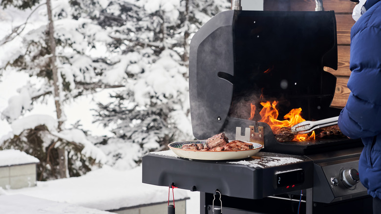 A person plates meat from the grill amid a snowscape.