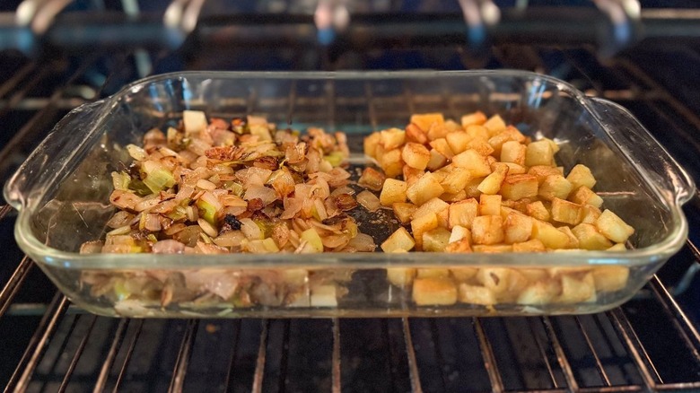 Sauteed onions and potatoes in clear baking dish in oven