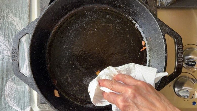 Wiping crumbs out of a cast iron skillet with paper towel