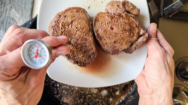 Filet mignon resting at 120 F on plate with instant read thermometer