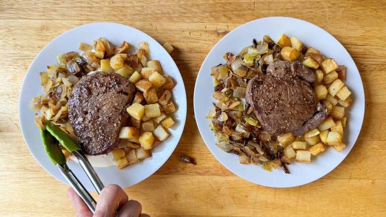 Adding cooked onions and potatoes to filet mignon on white plates