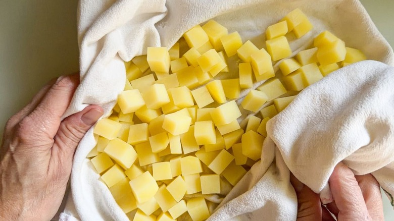 Drying cooked potato cubes with kitchen towel