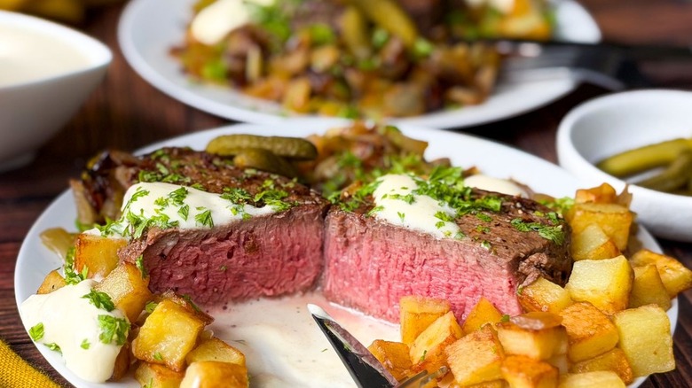 Beef Rydberg-style steak and potatoes with steak cut open on plate and cooked medium rare