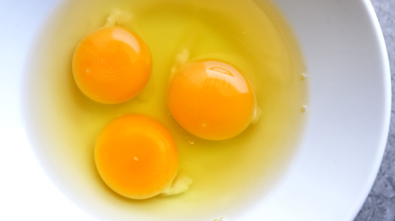 Bowl of raw eggs with three yolks