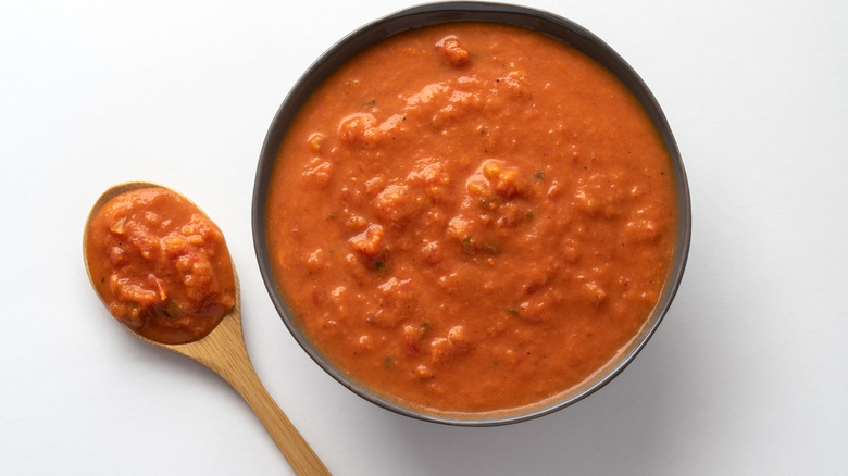 Vodka red sauce in a bowl and a spoon on a white background.