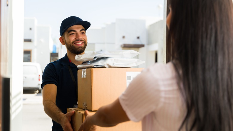 A delivery person handing packages to a homeowner