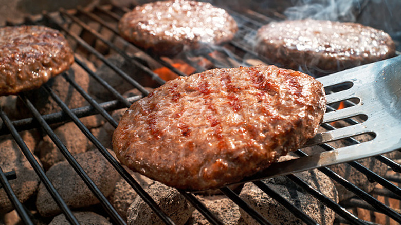 Burger patty with grill marks being lifted from the grill by a spatula