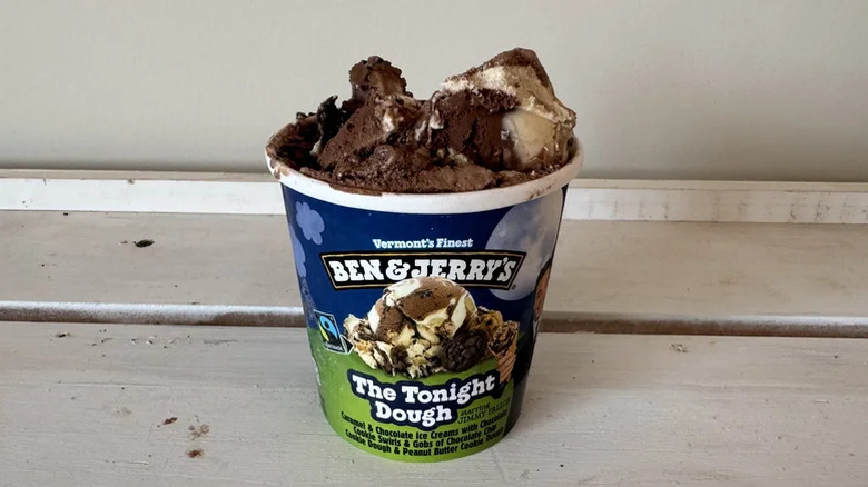 An opened tub of Ben and Jerry's Tonight Dough flavor with a small mound of ice cream on top.