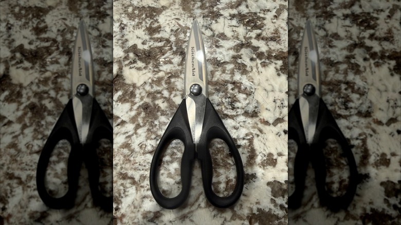 Black-handled stainless steel KitchenAid kitchen shears on a granite countertop