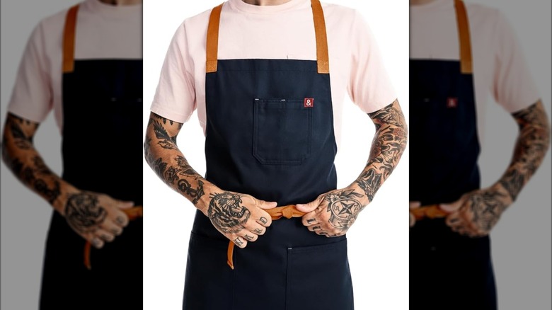 A man with tattoos wearing a blue apron