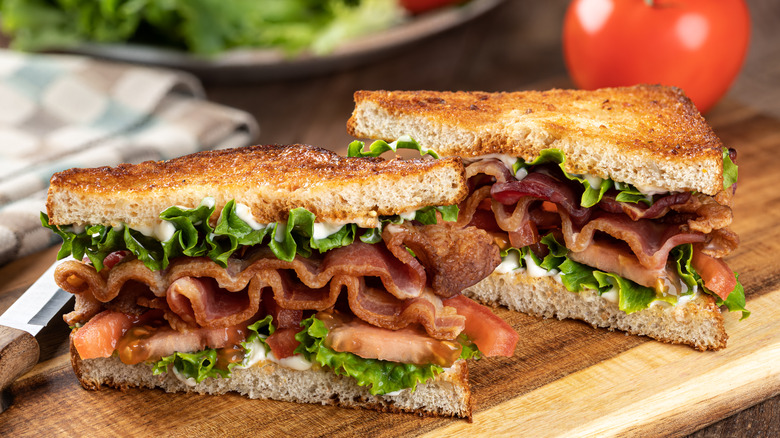 A BLT sandwich cut in half on a cutting board