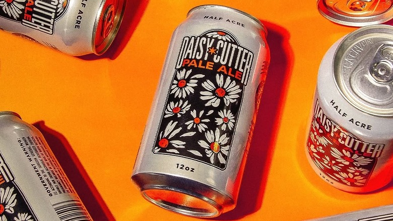 Cans of Half Acre Daisy Cutter Pale Ale on an orange background