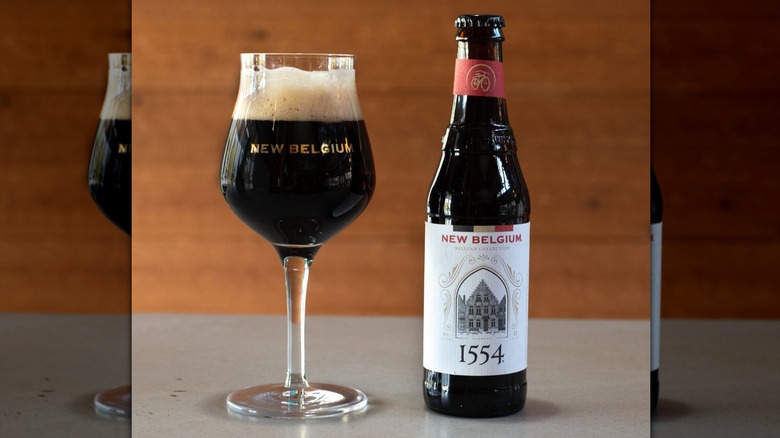 A bottle and stemmed glass of New Belgium 1554 Enlightened Dark Ale