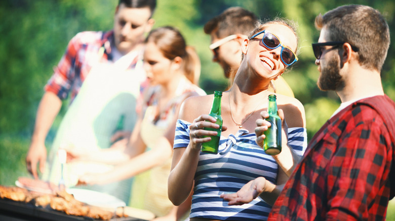 Group of friends drinking beer and grilling food at an outdoor gathering