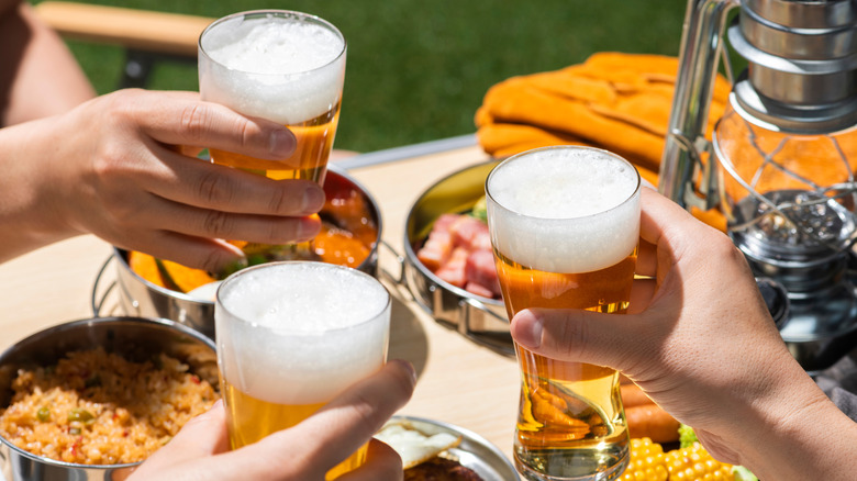 Hands toasting glasses of light beer outside