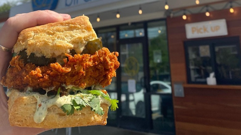 A person holding a fried chicken biscuit sandwich from Bird Bird Biscuit