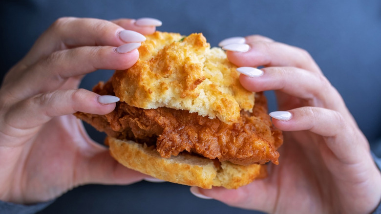 A person holding a fried chicken biscuit sandwich at Buttermilk Kitchen