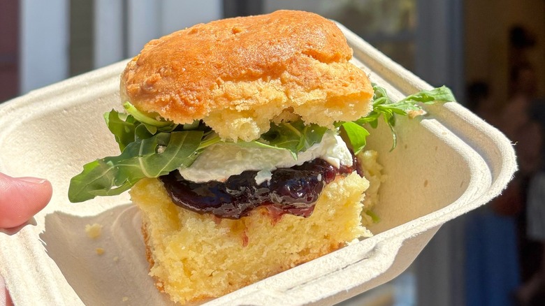 A person holding a takeout container with a biscuit sandwich from Callie's Hot Little Biscuit