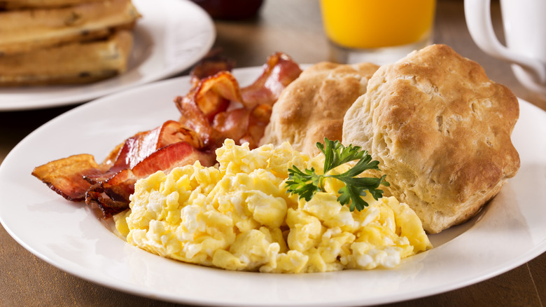 A breakfast plate with eggs, bacon, and biscuits at a restaurant