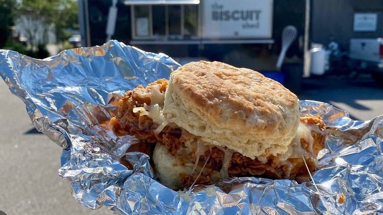 A person holding a biscuit sandwich in tin foil from the Biscuit Shed
