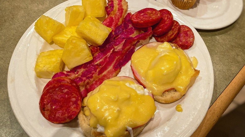 A plate of eggs Benedict with bacon, sausage, and pineapple at Garden Court at Main Street Station