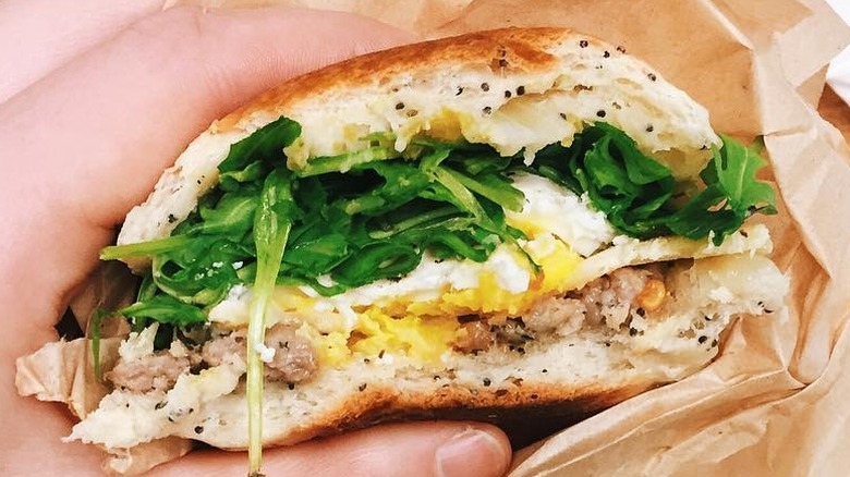 A person holding a Breakfast Sandwich at Fire Island Rustic Bakeshop in Anchorage