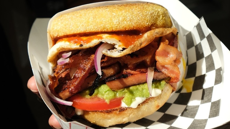 A person holding a Waikiki B.E.A.S.T sandwich at Munch n' Brunch in Honolulu