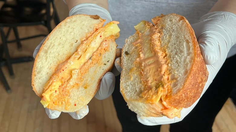 A person holding the North Dakota: Kimchi Egg & Cheese sandwich at Moonrise Cafe in Fargo