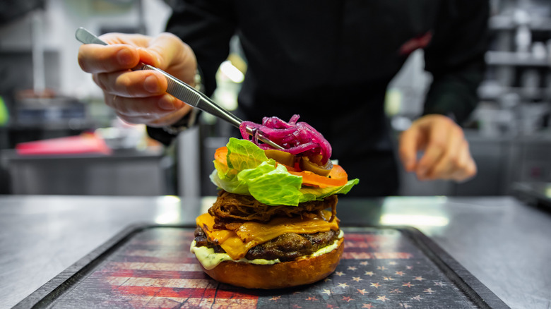 Chef topping burnt ends burger with slaw