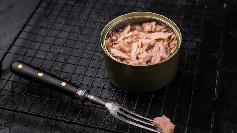 An opened can of tuna on a metal rack