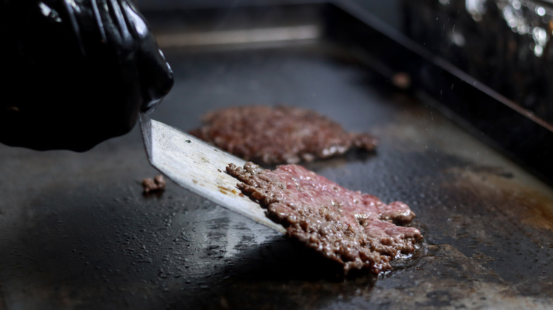 A smash burger is flipped with a spatula