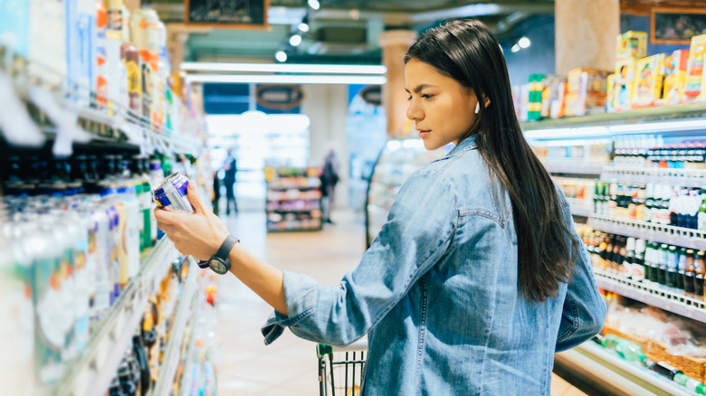 A woman looking at a can of beer