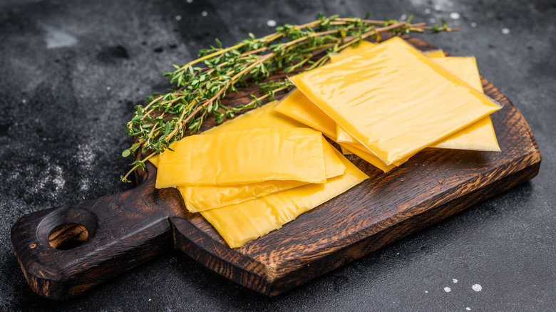 Processed cheese on cutting board with herbs