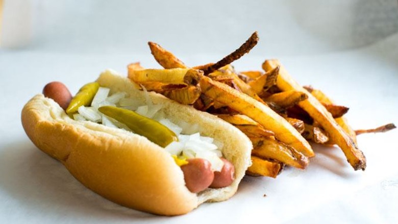 A Redhot Ranch hot dog with a side of French fries served on white paper
