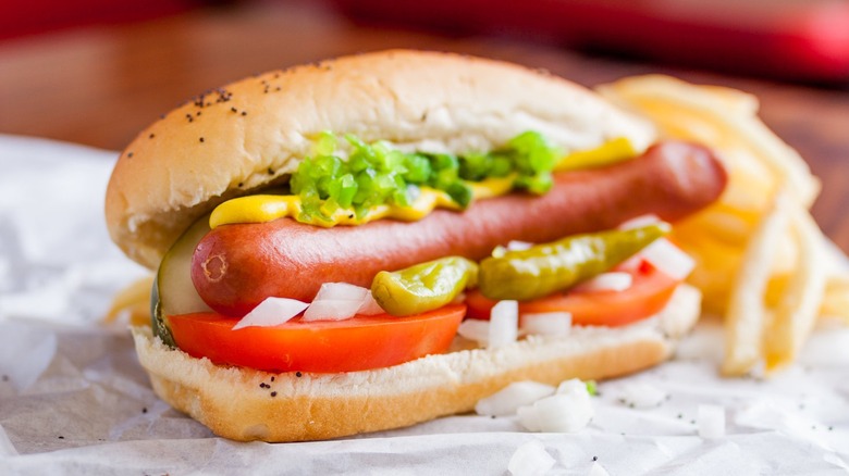 A Wolfy's Chicago-style hot dog served on white paper with French fries