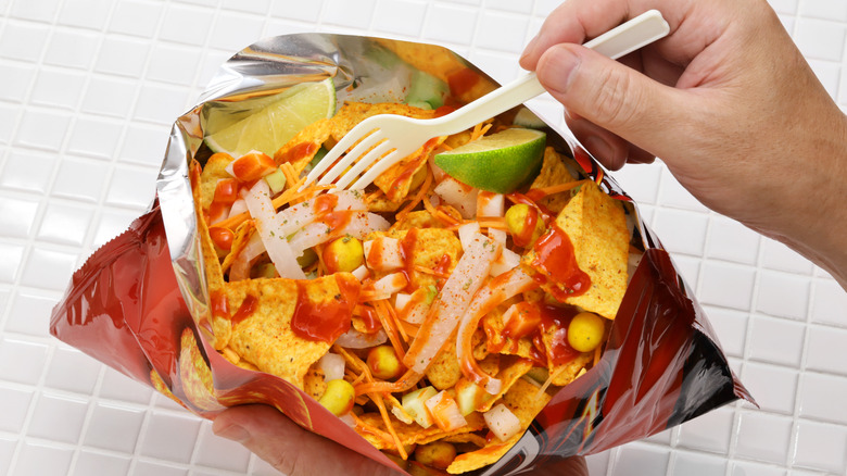 Hand holding a fork in a walking taco in a Doritos bag.