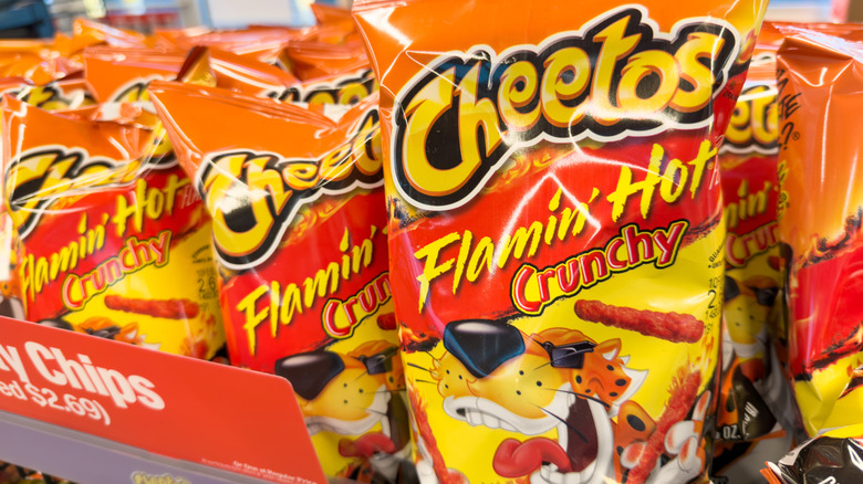 Bags of flamin' hot Cheetos on a store shelf.