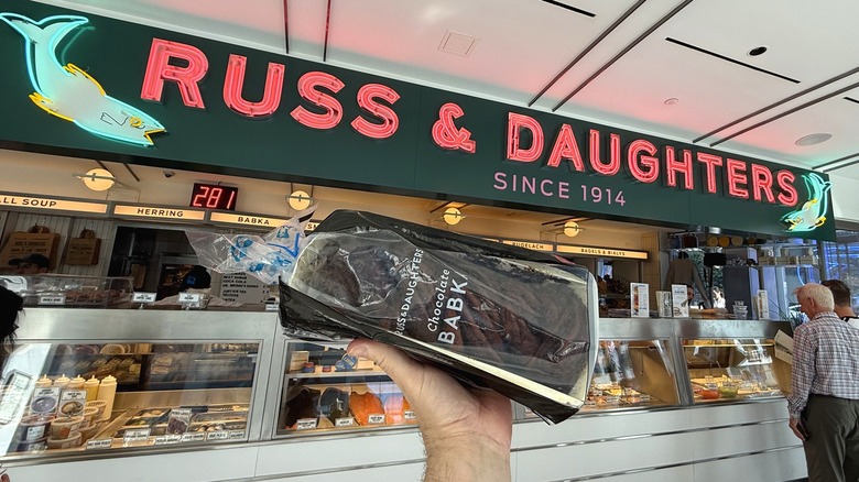 A chocolate babka held below the Russian & Daughters sign