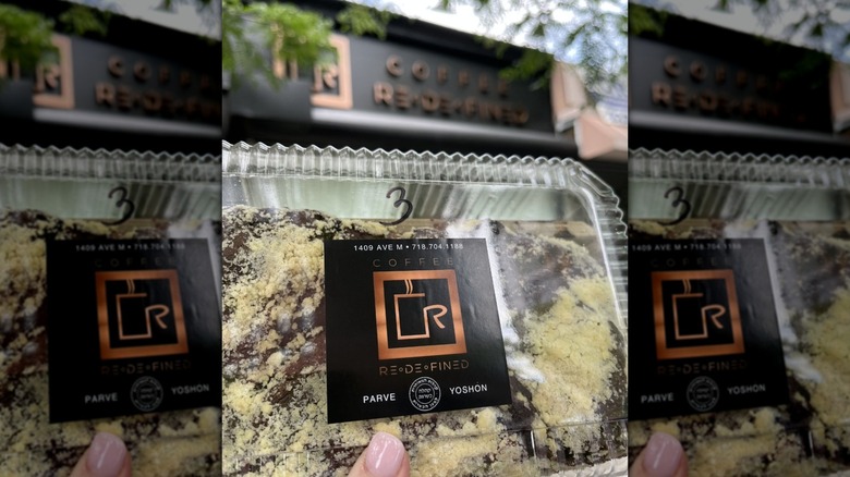 a babka held below the Coffee Redefined sign