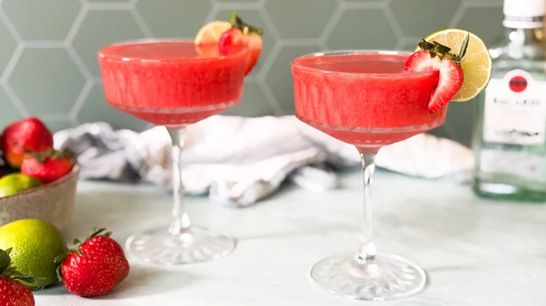 Two frozen strawberry daiquiris with strawberry and lime garnish