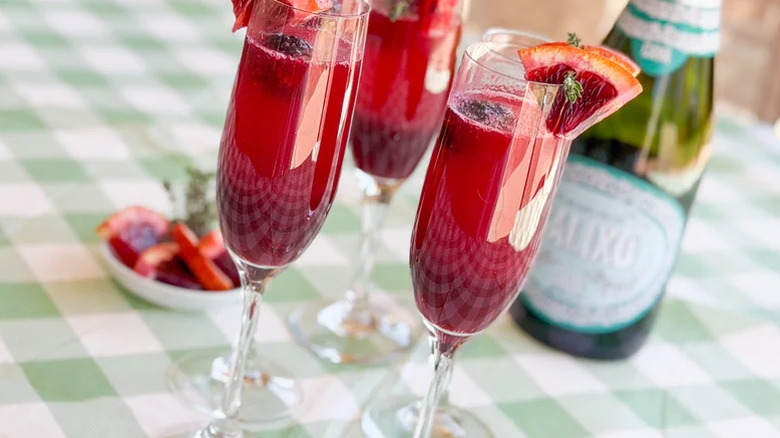 Close up of mixed berry blood orange mimosas in champagne glasses