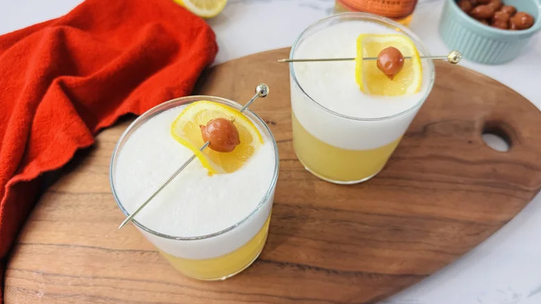Two glasses of whiskey sour with egg white foam