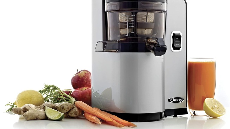 Produce and a glass of juice near an Omega juicer