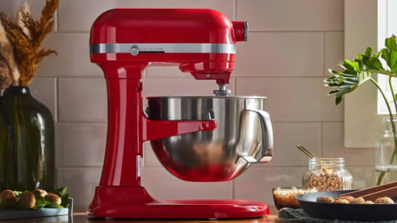 A red KitchenAid stand mixer on a counter in front of a tile backsplash